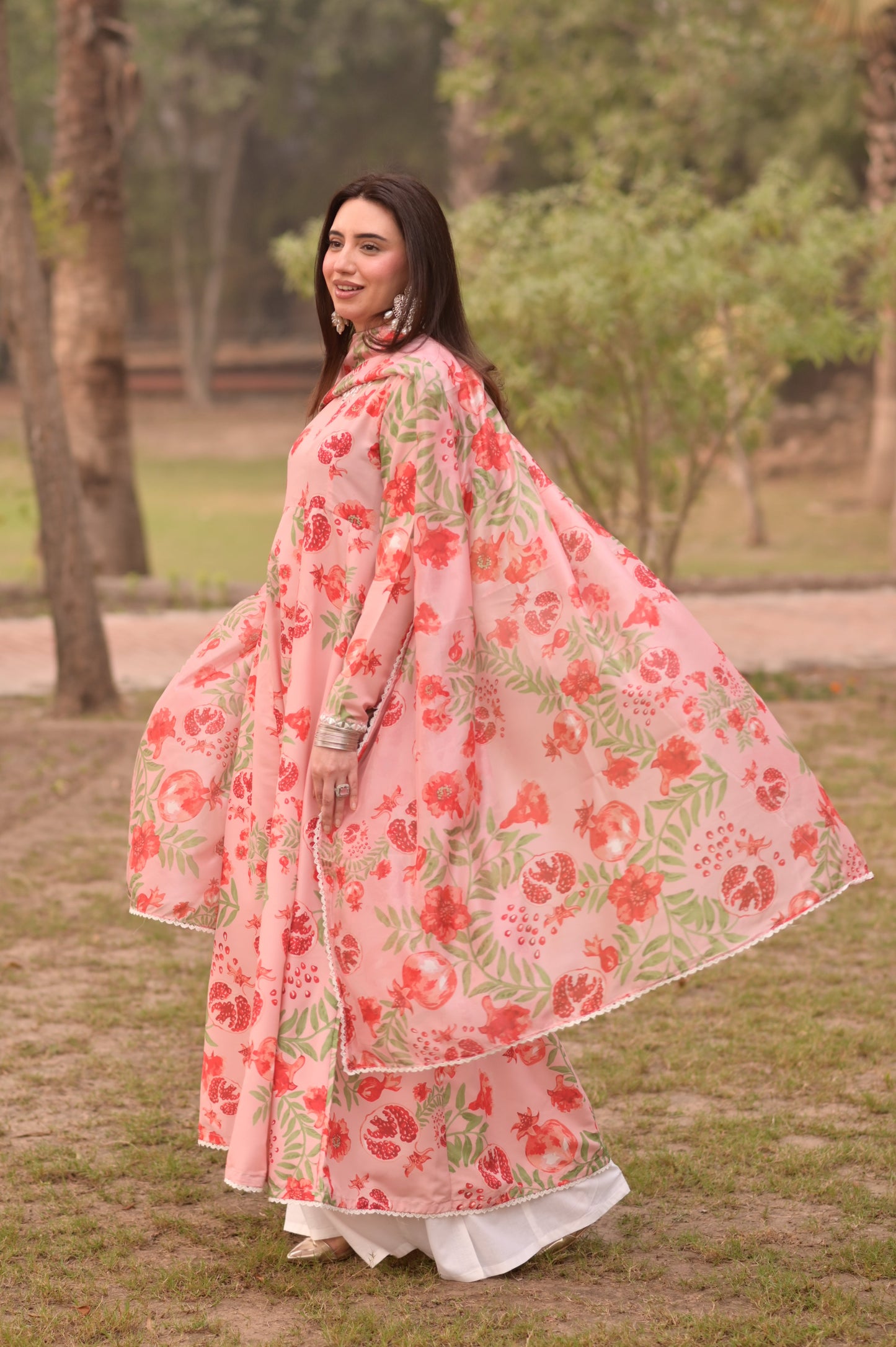 Woman in a floral dress standing outdoors with trees in the background