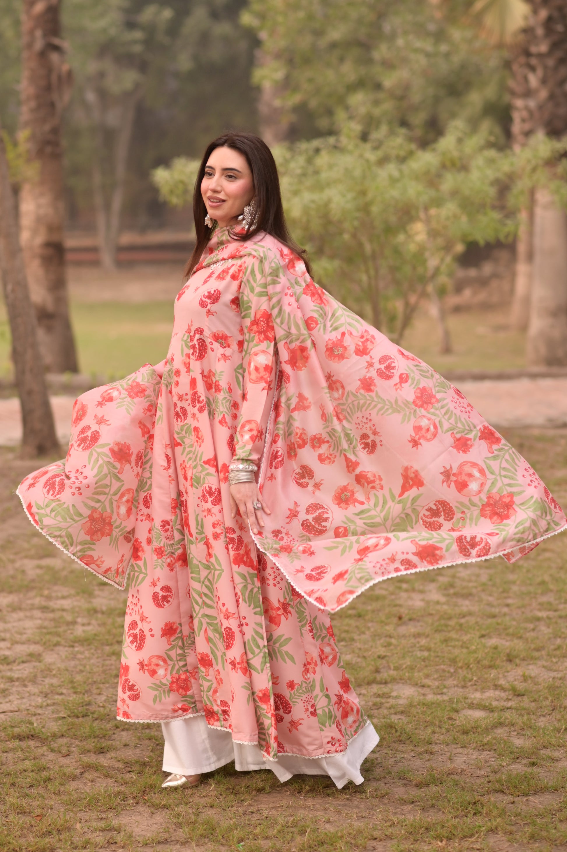 Woman in a floral dress standing outdoors with trees in the background